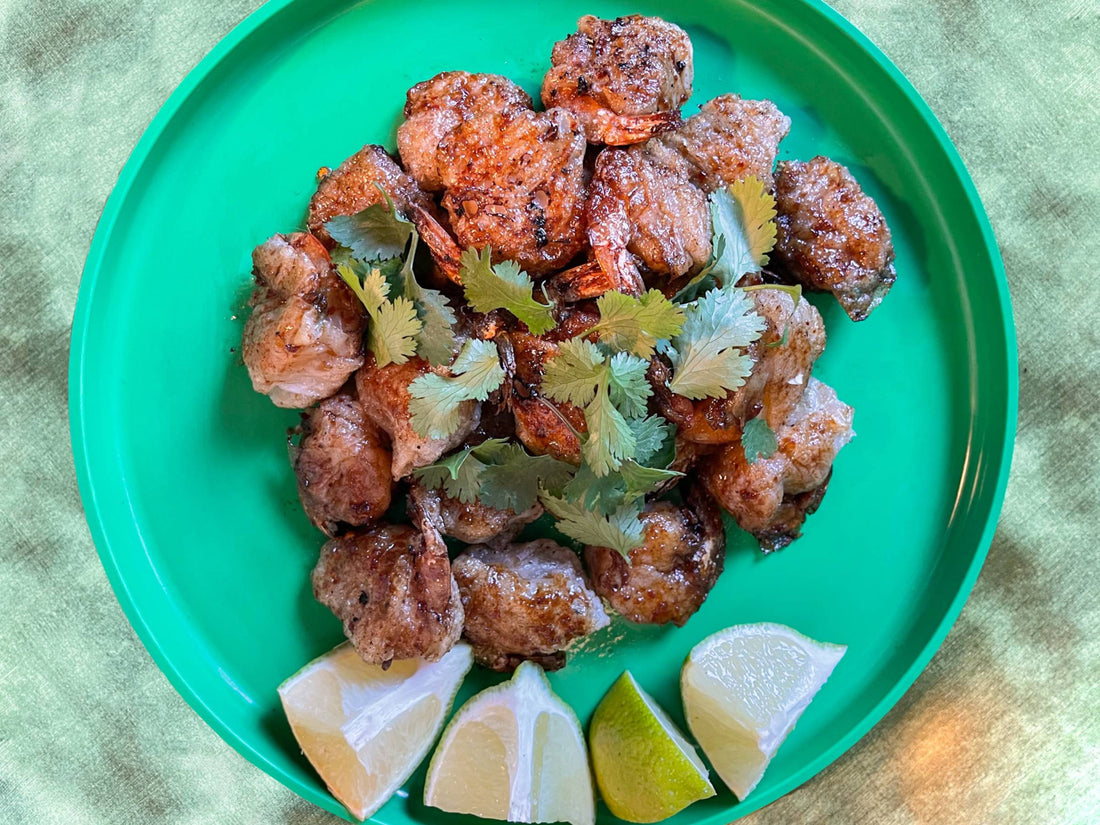 Top-down view of Krapow shrimp rice paper wraps on a bright green plate, served with lime wedges.