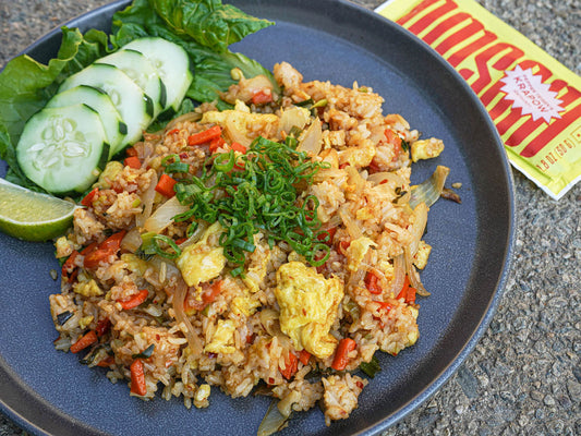 Thai krapow fried rice served on a blue plate. The meal starter packet lies next to the finished dish.