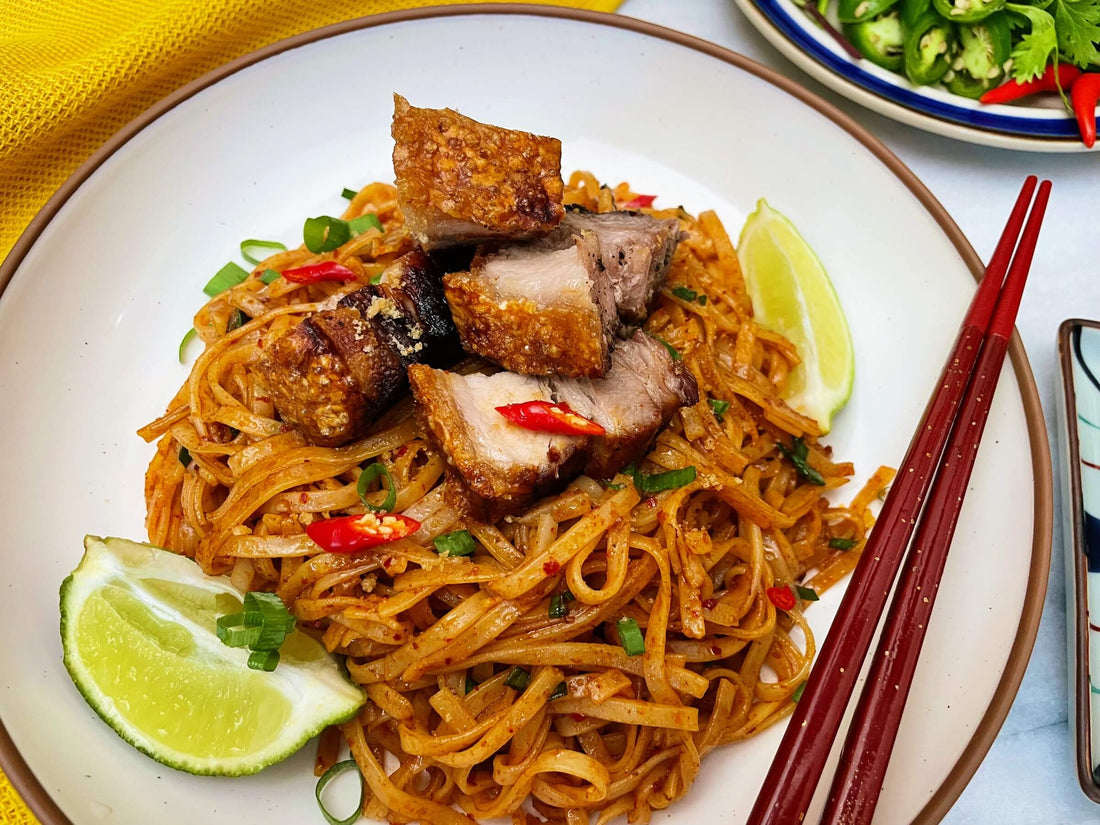 Top-down view of a noodle dish on a plate, served with chopsticks.