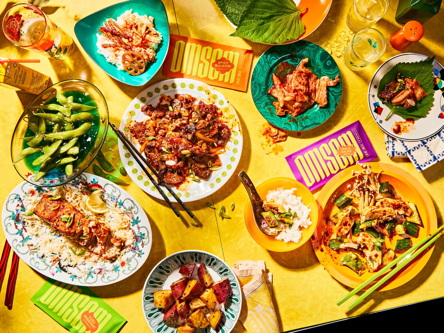 A yellow table with a variety of prepared dishes and meal starter packets